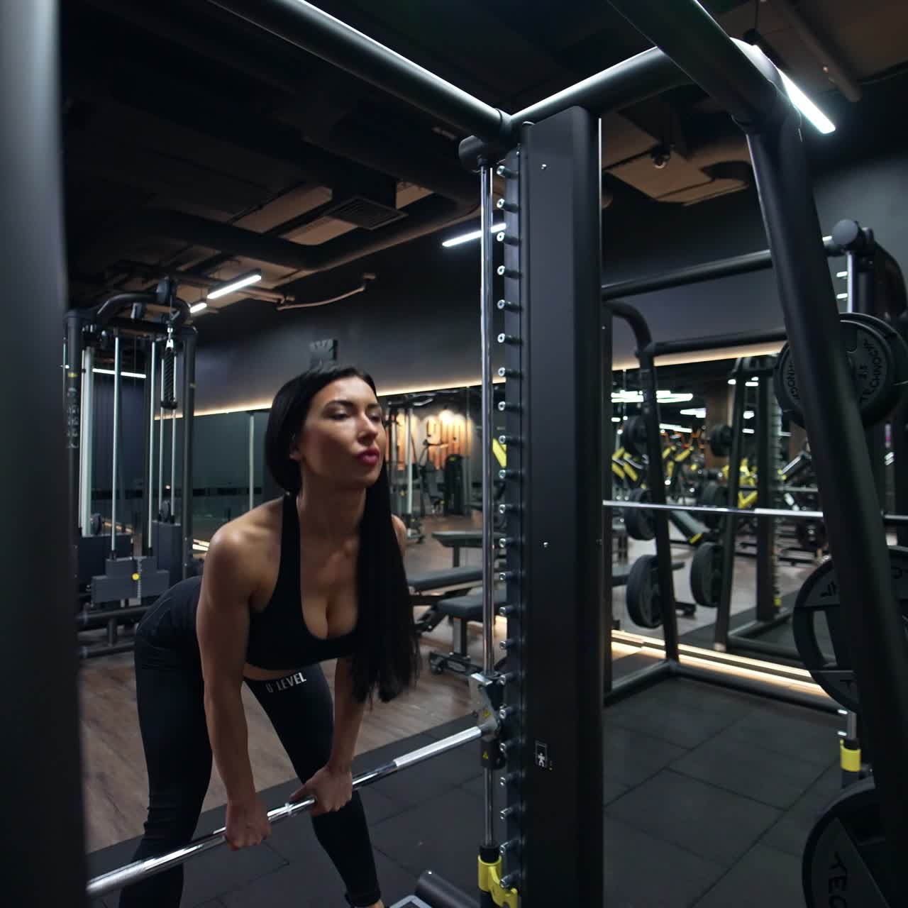 Mujer deportista delgada haciendo ejercicio en el gimnasio. Mujer levantando pesas para ejercitar brazos y espalda