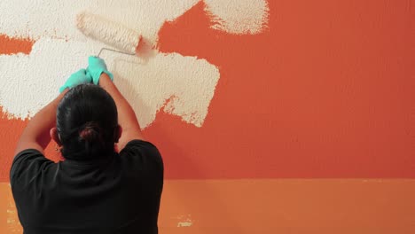 Trabajador-Usando-Un-Rollo-De-Pintura-Para-Pintar-Una-Pared-Naranja-En-Color-Blanco