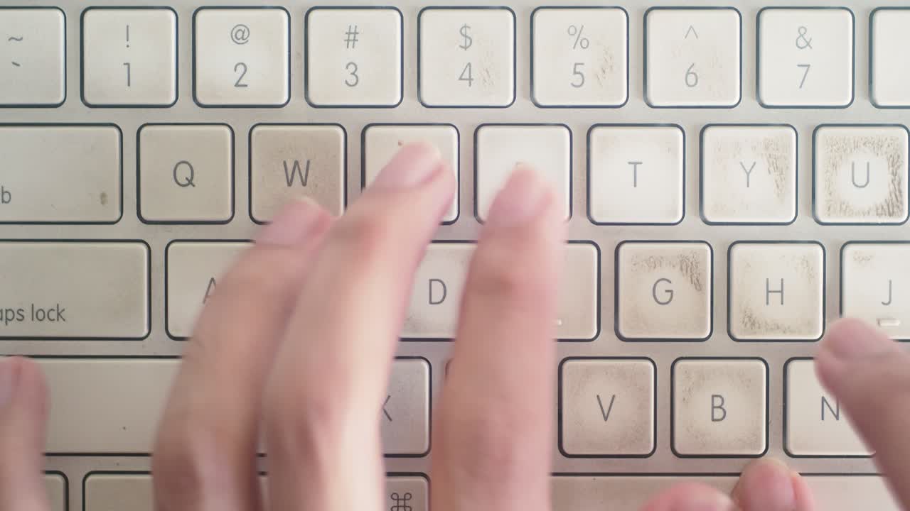 plano medio de manos escribiendo en un teclado mac desgastado