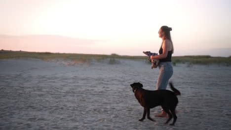 Mujer-Pasea-A-Su-Perro-Descalzo-En-La-Playa-Mientras-Se-Pone-El-Sol