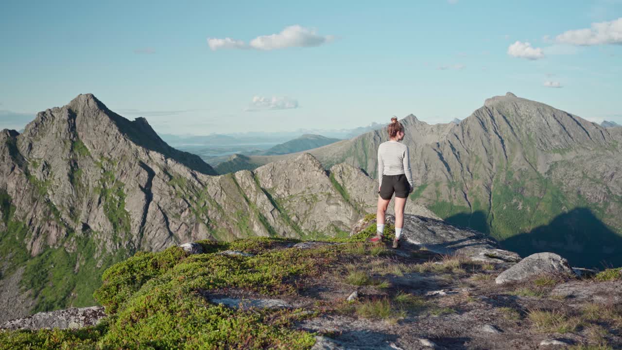 Female Hiker Walking At Headland With Rocky Hills In Background During Summer In Norway. - Static Shot