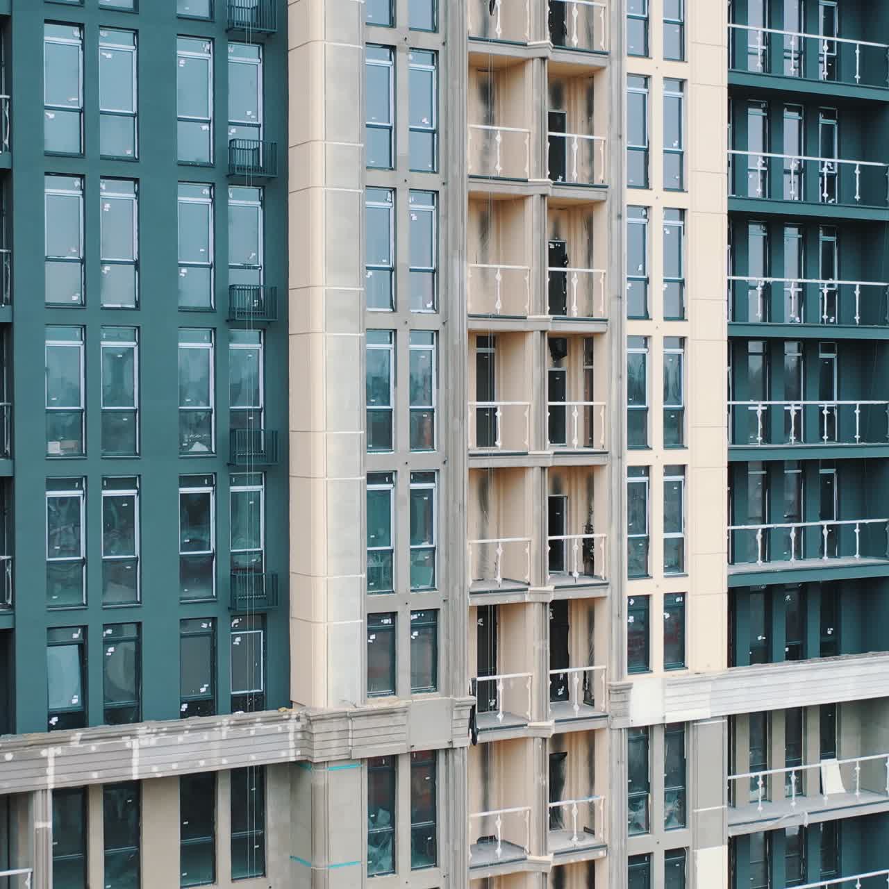 Tall apartment building. Construction of a multi-storey apartment building with windows and balconies. Camera rising up.