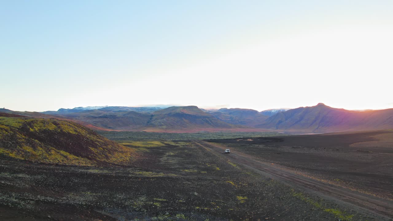 vista aérea de un land rover blanco conduciendo por una carretera islandesa con un impresionante fondo montañoso