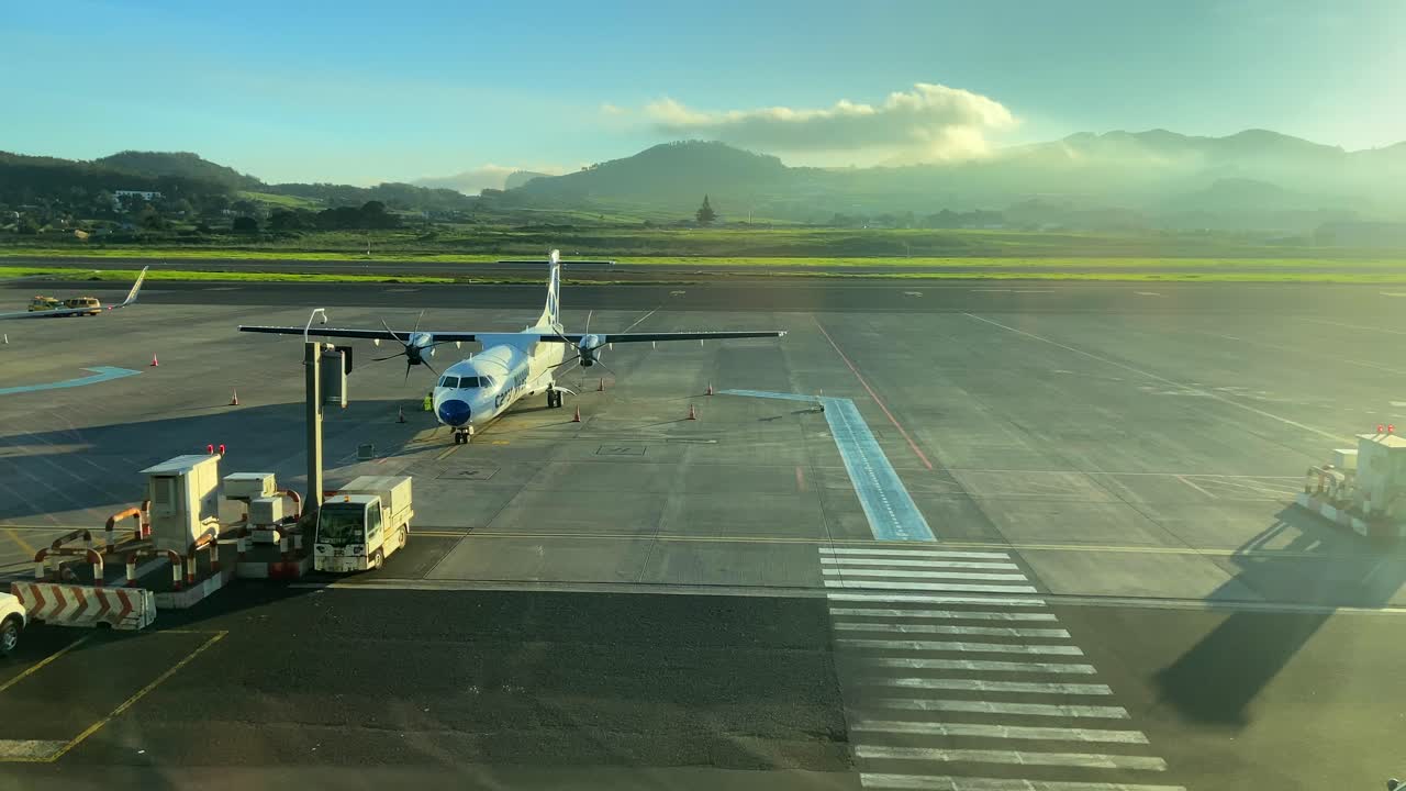 vista estática de un avión comercial en la pista de aterrizaje de un aeropuerto de una isla tropical al atardecer