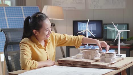 side view of asian woman being happy succeed building a model of small house with solar panel