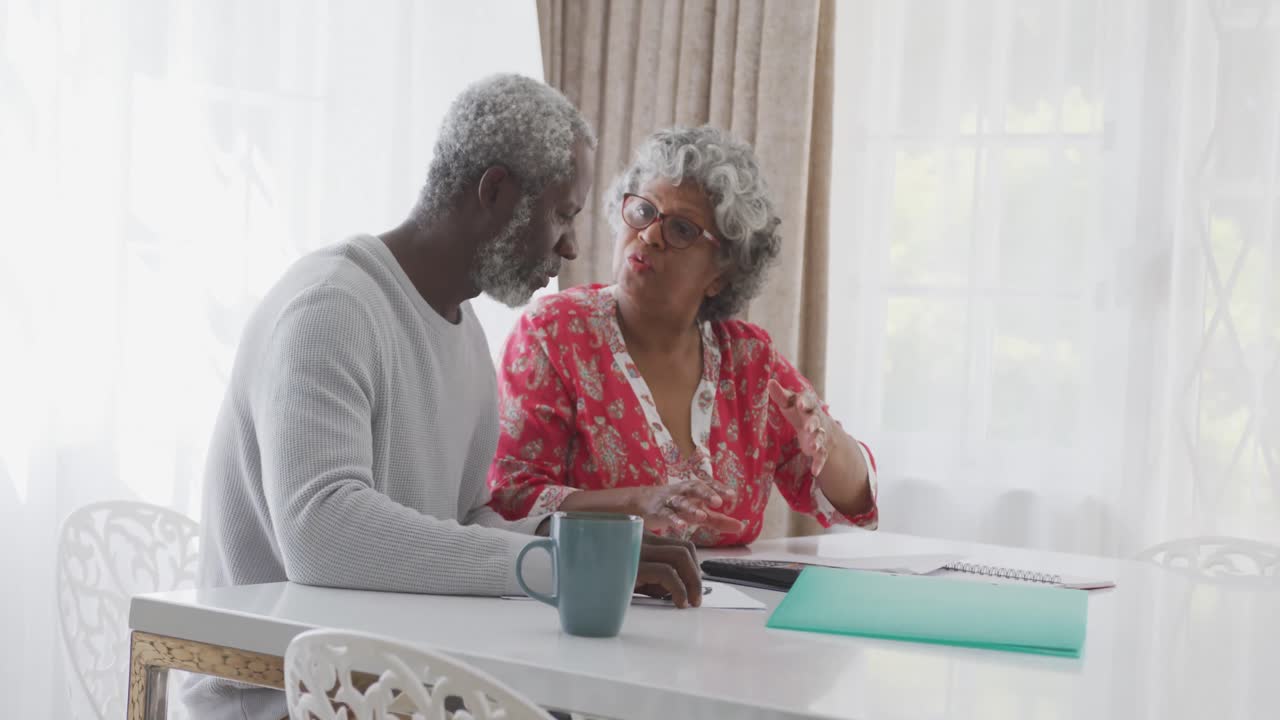 A senior African american couple at home, working on papers in social distancing