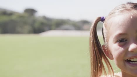 portrait of happy caucasian girl on sunny elementary school playing field, copy space, slow motion