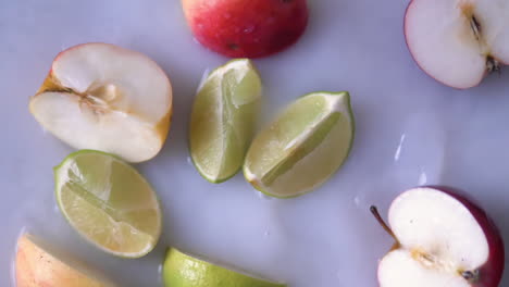 Rodajas-De-Limón-Fresco-Cayendo-En-Agua-Lechosa-Decorada-Con-Manzanas-Frescas