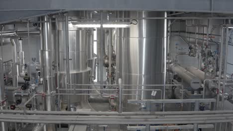 interior view of industrial processing area with large, shiny stainless steel tanks and intricate piping network, castets, france