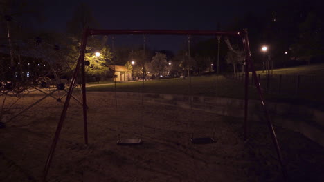 Bewegliche-Schaukelsitze,-Leerer-Kinderspielplatz-Bei-Nacht,-Prag,-Tschechien,-Sperrung