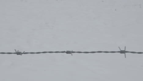 dolly over barbed wire with snow in the background