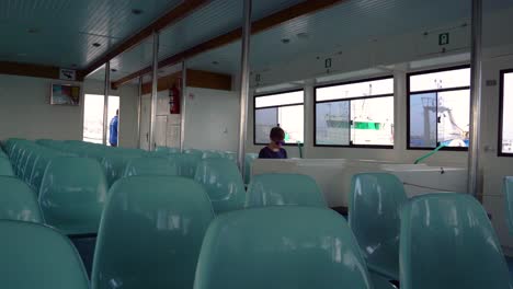 A-boy-in-the-sunglasses-sits-on-a-bench-and-uses-his-phone-while-traveling-in-a-Spanish-ferry