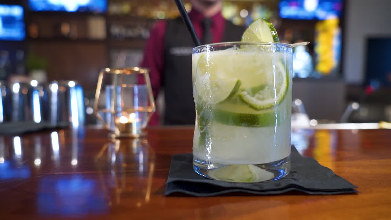 el camarero sirve la bebida nacional de brasil caipirinha adornada con limas, el control deslizante se cierra en cámara lenta 4k
