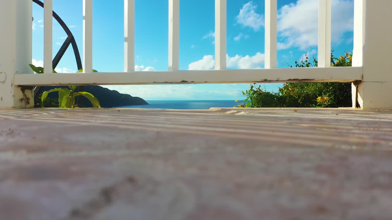Forhøjet nærbillede afslører et hvidt hegn i forgrunden, havet glimter i det fjerne, og tæt skov langs horisonten.