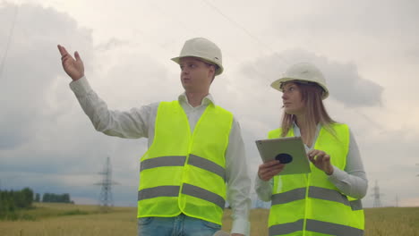 líneas eléctricas un hombre y una mujer ingenieros con una tableta en sus manos discutiendo el progreso del proyecto de construcción