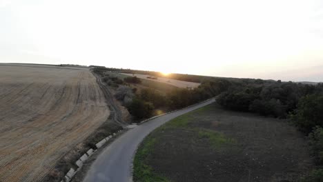 drone volando en llanuras con camino aislado durante la puesta de sol
