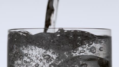 agua vertiendo sobre hielo en un vaso alto para beber