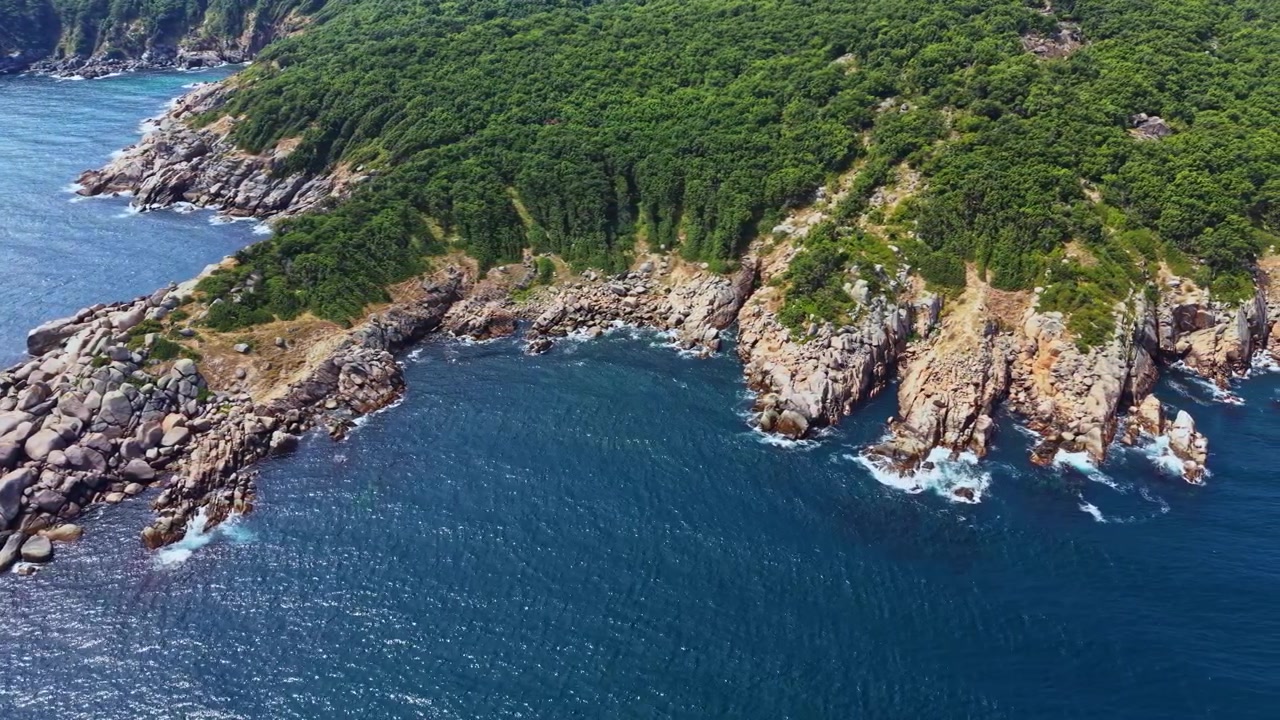 Vista della costa che mostra rocce, terra e oceano vicino a un'area boschiva di giorno in una regione tropicale