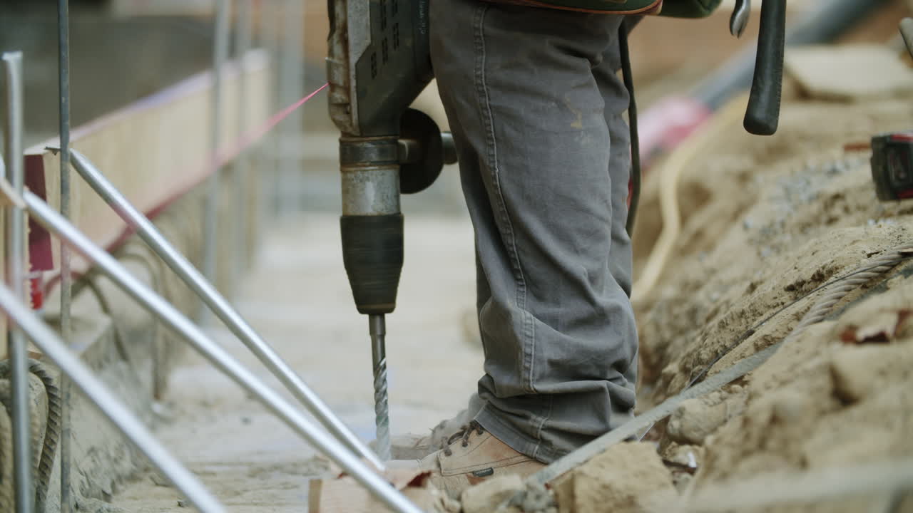 Construction worker operating a drill or jackhammer on a building site