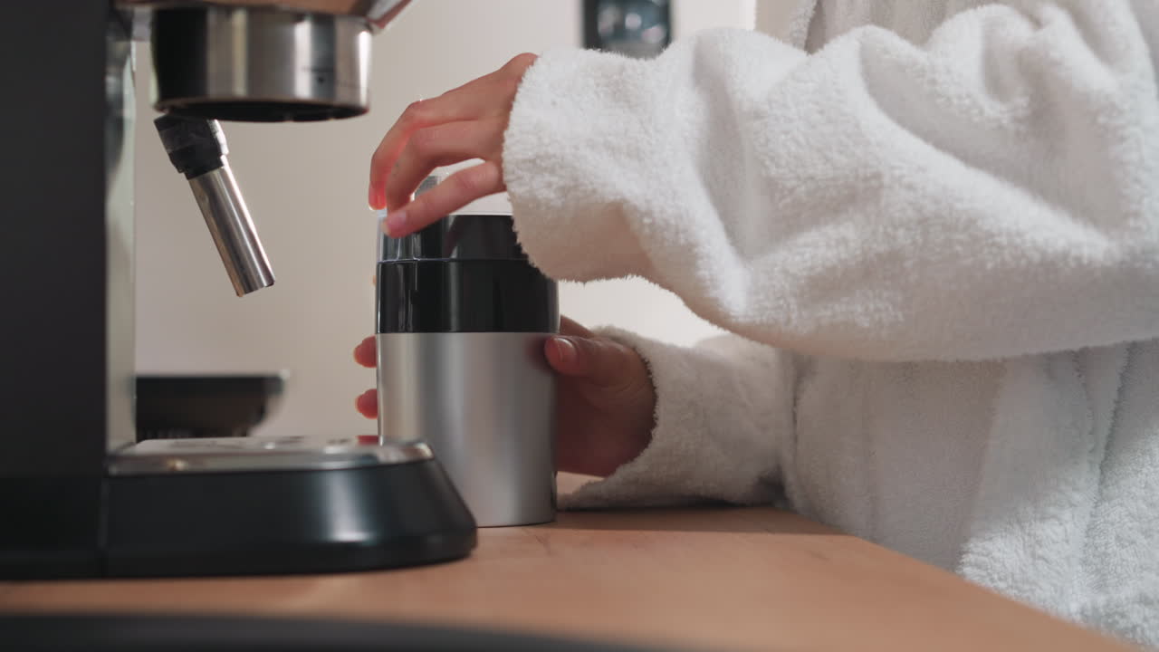 테이블 클로즈업에서 여성이 밀러 장치를 닫습니다. 쾌적한 욕조를 입은 여자가 커피 콩을 밀어낸 후 밀러를 닫는다. 음료 준비 과정