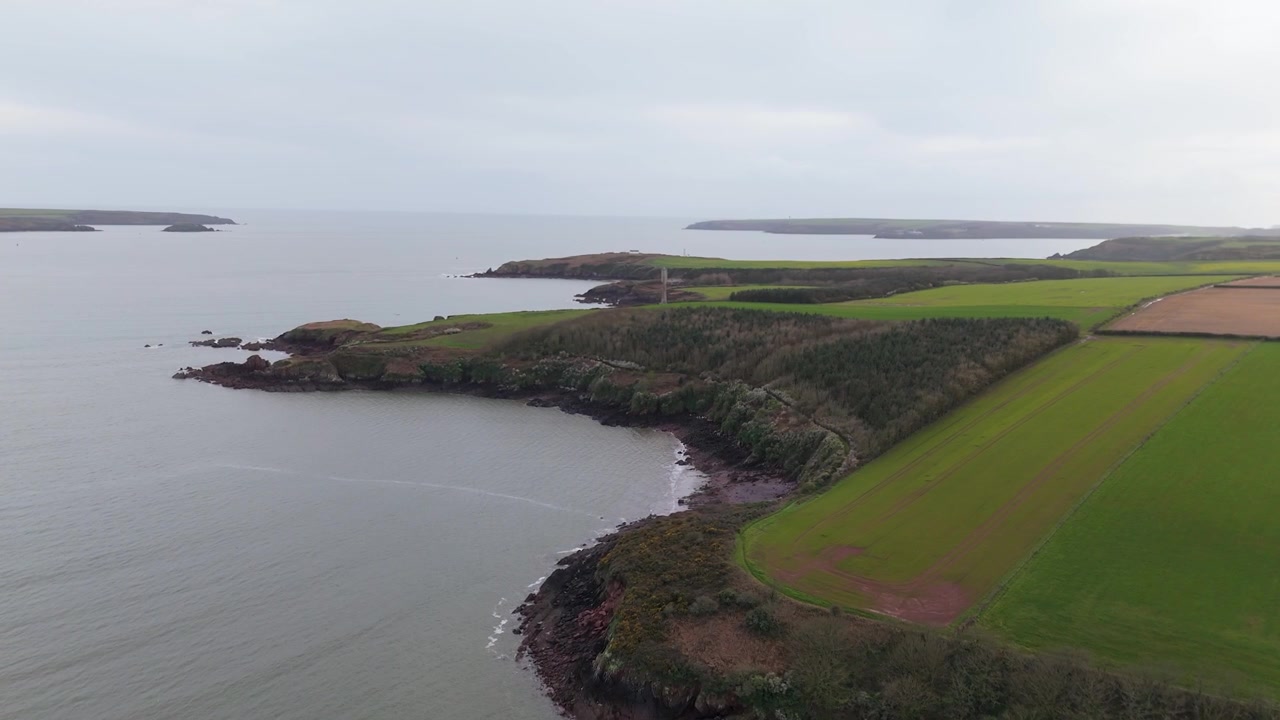 Pembrokeshire: Paesaggio aereo di un campo costiero con faro a Sleeping Bay a Milford Haven, Galles, Regno Unito. Ripresa rotante