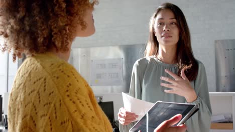 Happy-diverse-female-colleagues-with-tablet-and-documents-discussing-work-in-office,-slow-motion