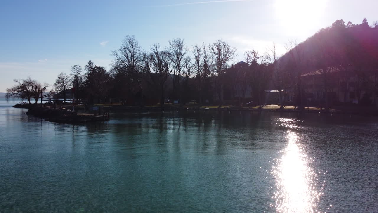Drone view of peaceful lakeside landscape at sunset on Lake Balaton with long tree shadows