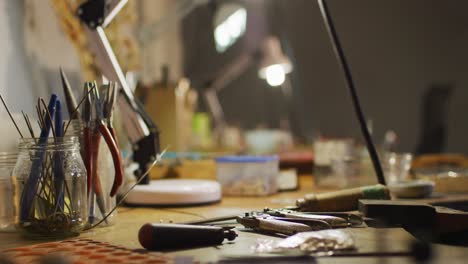 Close-up-of-diverse-jeweller-tools-lying-on-desk-in-workshop