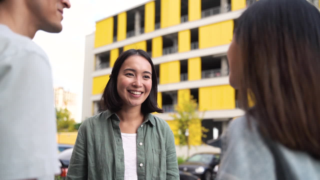 Group Of Three Happy Young Japanese Friends Standing Outdoors And Talking To Each Other 3