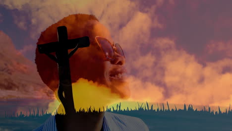 smiling person in front of cross with vibrant sunset sky in background