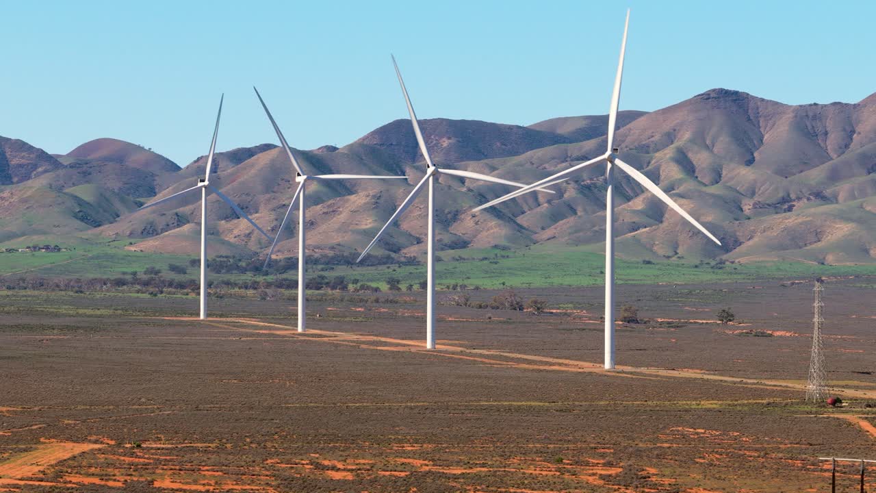 Fast aerial orbit with telephoto drone around wind turbines and hills in South Australia