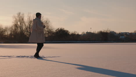 woman enjoying a winter sunset on a frozen lake