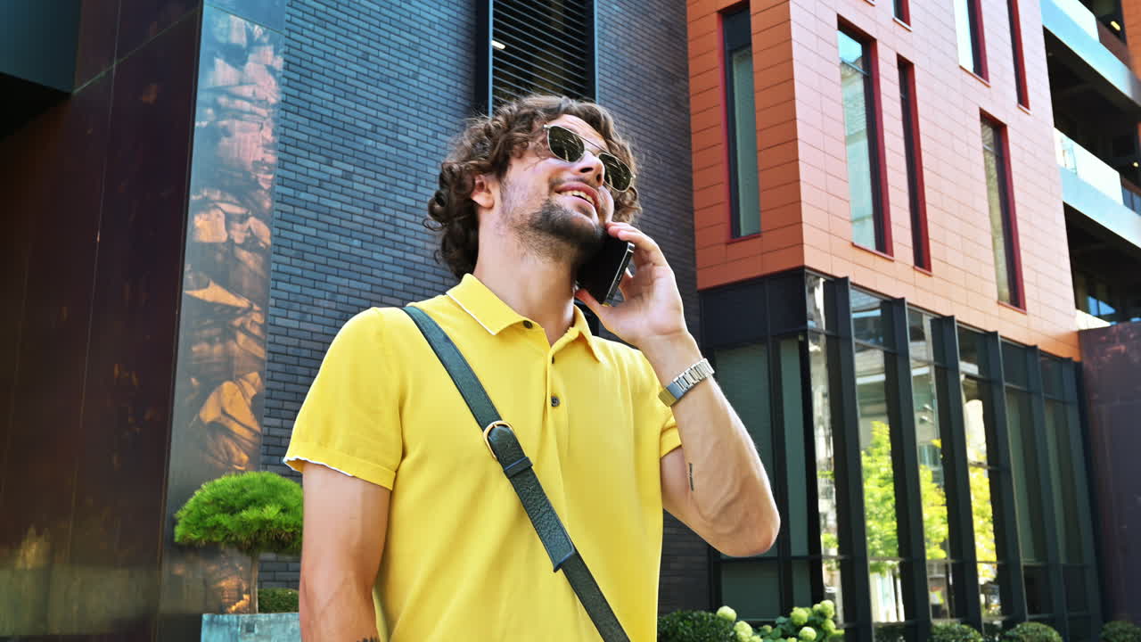 Man in yellow shirt talking on the phone while walking on the street