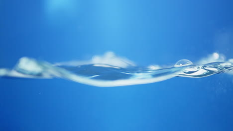 Vista-Macro-De-Dinámica-De-Fluidos-De-Gotas-De-Agua-Dulce-En-Movimiento-Sinfonía-De-La-Naturaleza-Efecto-De-Ondulación-Del-Agua-En-Cámara-Lenta-En-Tono-Azul