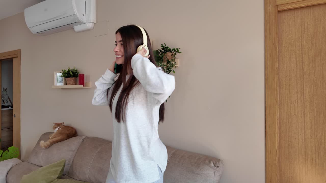 Woman dancing to music with headphones at home