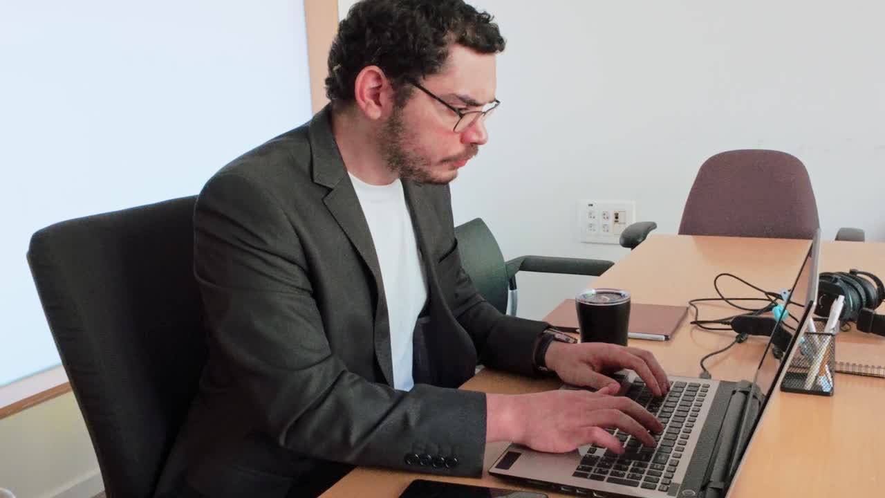 young businessman with glasses, deeply concentrating on his laptop