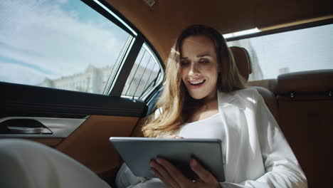 surprised business woman reading good news on tablet computer in luxury car.