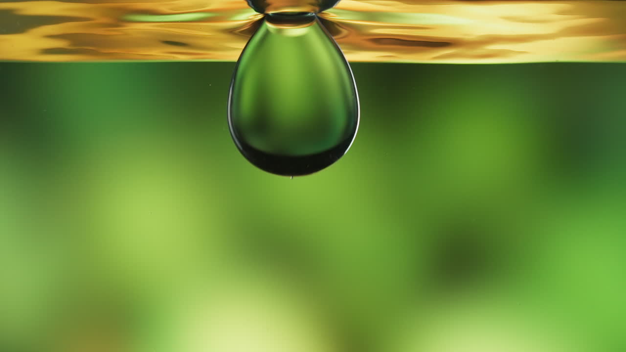 Pure, virgin olive oil with a large drop dipping