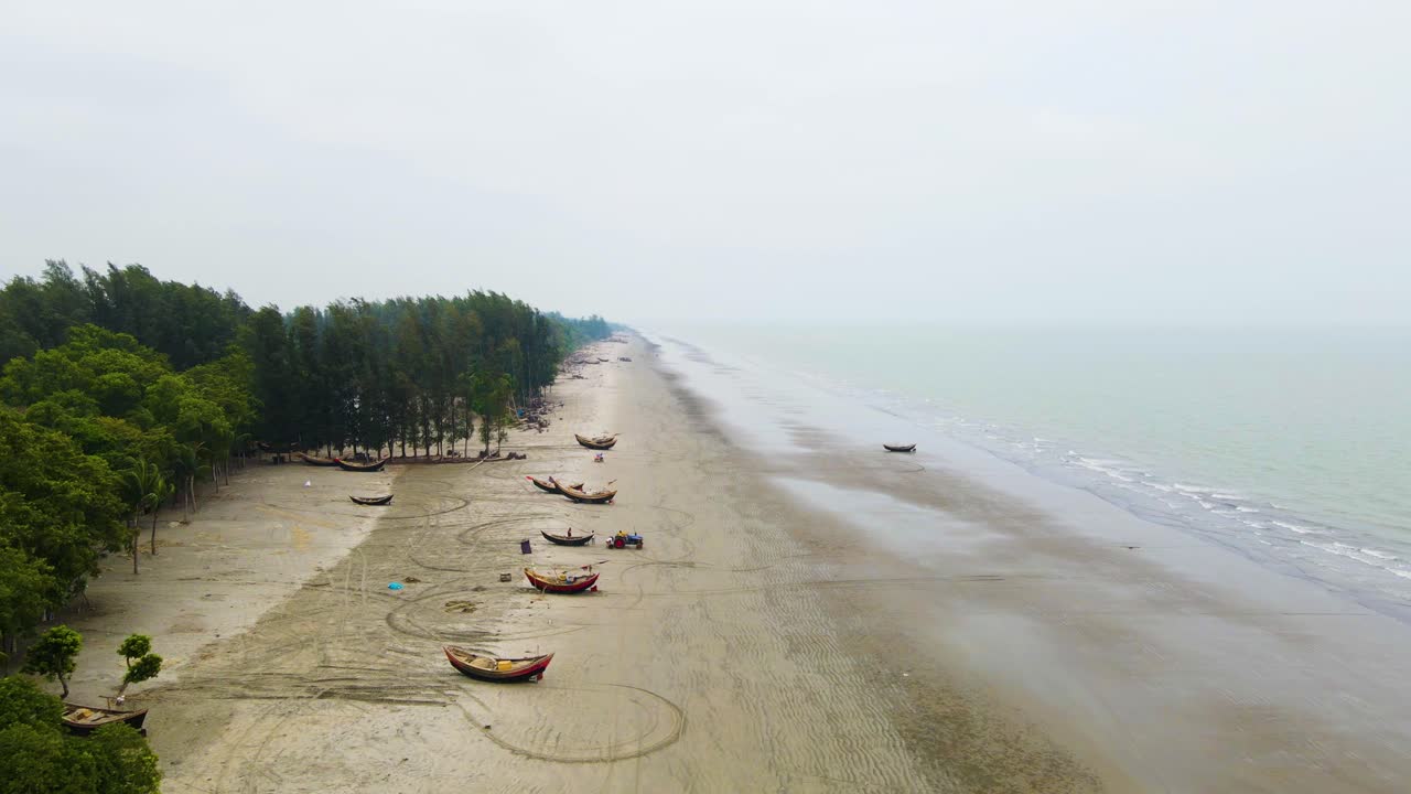 una foto aérea de una costa de playa mientras los pescadores preparan sus botes en una mañana de niebla en kuakata, bangladesh