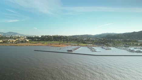 drone establishing tracking right across protected harbor of carquinez strait with wetlands and shoreline in martinez, california, during tranquil midday