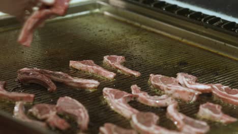 Primer-Plano-De-Colocar-Chuletas-De-Cerdo-Crudas-En-Una-Parrilla-De-Restaurante