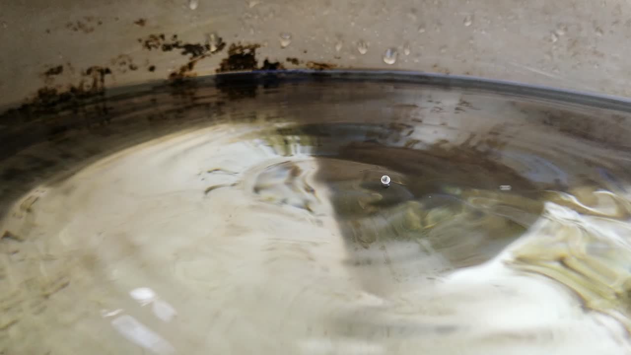 양동이 내부의 파이프에서 새는 물 방울의 매크로 근접 촬영, 잔물결