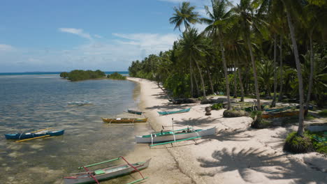 aerial showing wooden fishing boats on union beach, siargao island, philippines