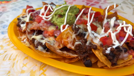 Nachos-Mexicanos-Tradicionales-Tex-mex-Con-Chili-Con-Carne-De-Ternera,-Guacamole,-Queso-Derretido-Y-Crema-Agria,-Chips-De-Tortilla-Totopos,-Comida-Sabrosa,-Toma-De-4k