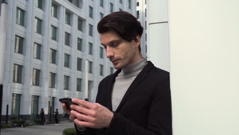 joven caucásico usando el teléfono celular. enviando mensajes de texto y sintiéndose feliz. concepto de oportunidades de carrera corporativa