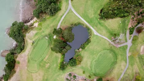 Vista-Aérea-De-Un-Campo-De-Golf,-Vista-Desde-Arriba-Con-Una-Gran-Cortadora-De-Césped-Corriendo-En-Music-Point,-Auckland,-Nueva-Zelanda