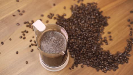 french press surrounded by coffee beans