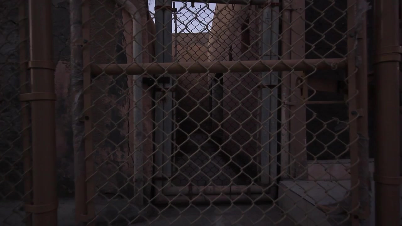 Acercamiento con dolly a una puerta de malla de alambre en un lugar espeluznante conocido como el antiguo museo en una zona rural del este de Arabia Saudita