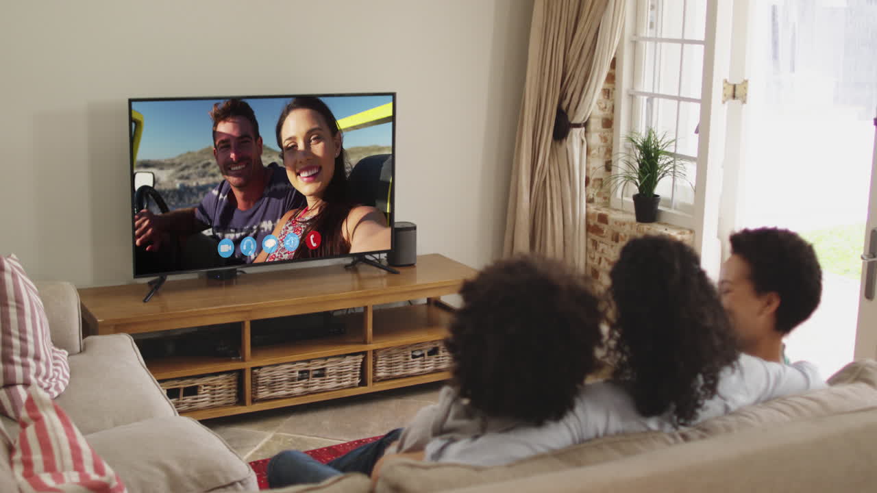 Famiglia afroamericana che fa una videochiamata in TV mentre è seduta sul divano a casa