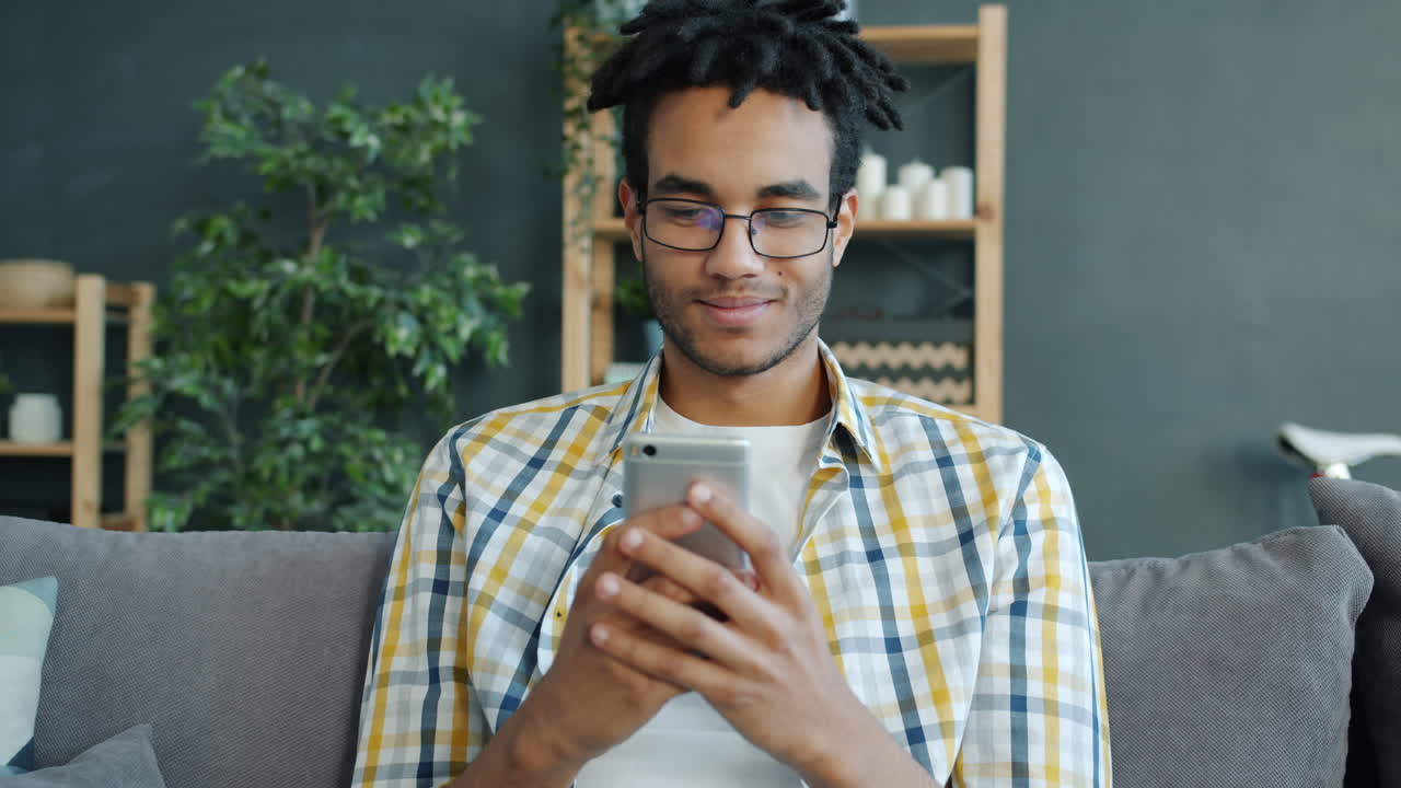 Giovane uomo che usa lo smartphone sul divano